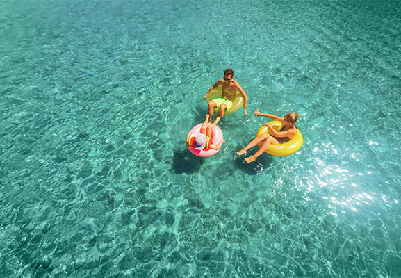 parents et enfant se relaxant sur des bouées gonflables sur l'eau