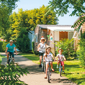 Famille faisant du vélo dans les allées d'un camping